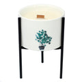 White ceramic candle holder with teal botanical tree print and black iron tripod stand